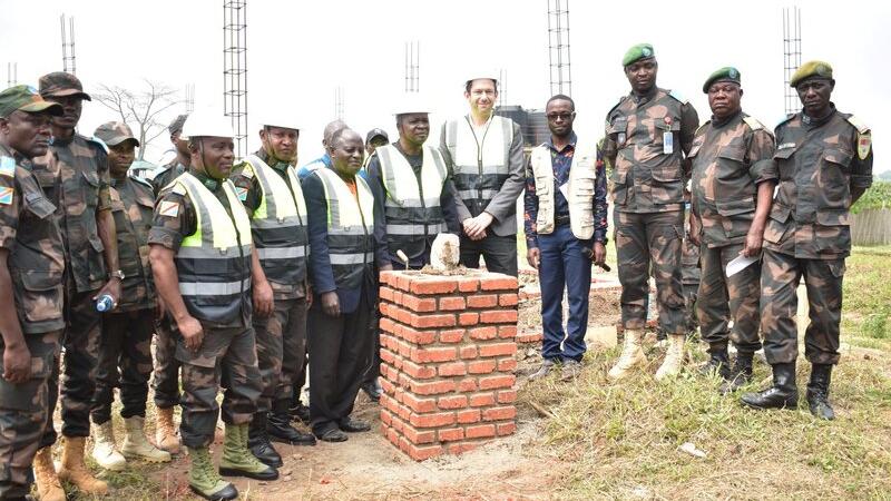 Un groupe pose pour une photo à côté d'une structure en briques.