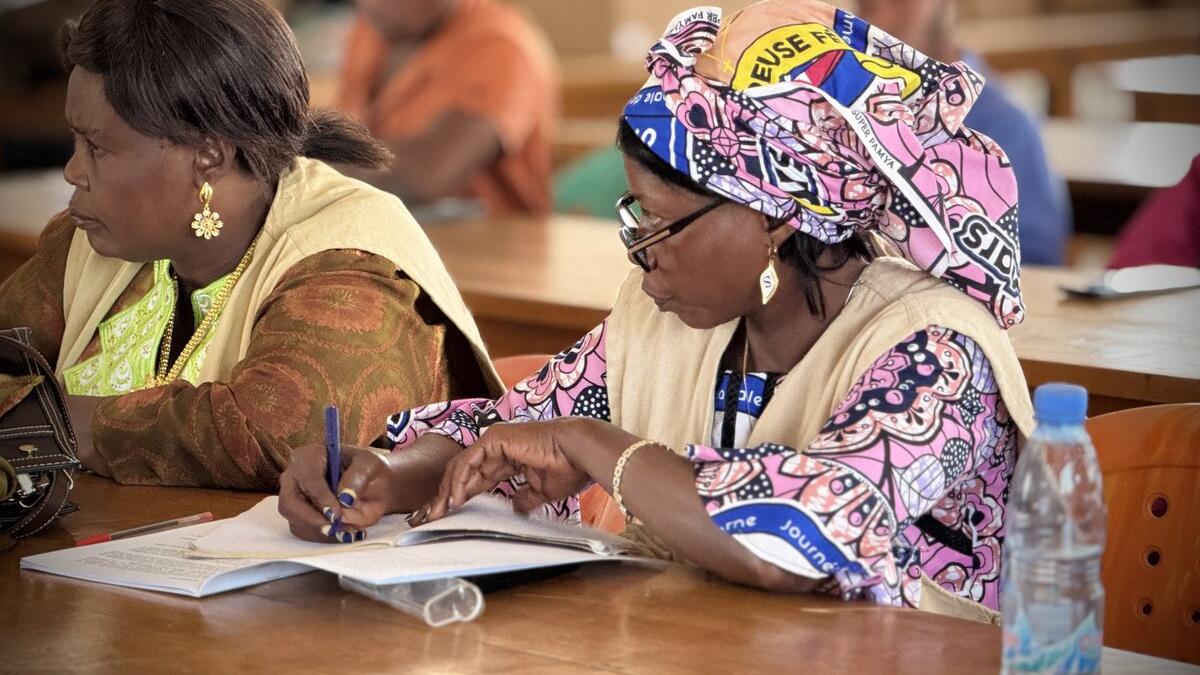 Un participant à une réunion écrit dans un carnet.
