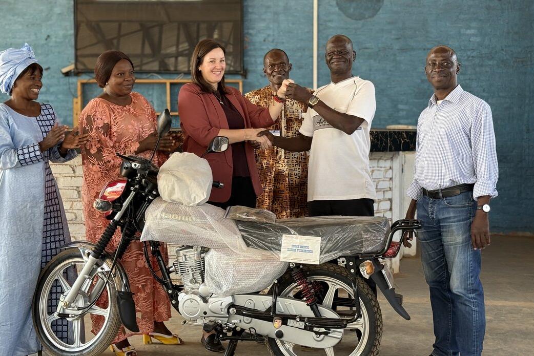 Des représentants posent pour une photo à côté d’une moto. 