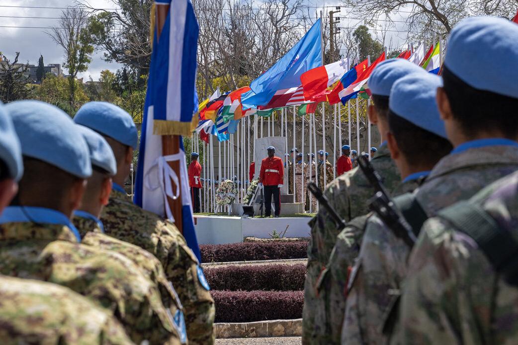 Peacekeepers stand in line and face a stage.